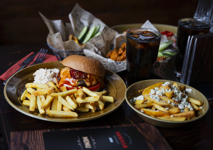 Zarillo-ravintolan valikoimaa: burger-annos ranskalaisilla ja siipiateria korissa lisukkeineen.